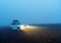 Poor weather visibility. White travel car in the night fog with
