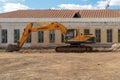 Russia, Kazan - April 20, 2019: Yellow excavator on the background of an abandoned building.