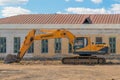 Russia, Kazan - April 20, 2019: Yellow excavator on the background of an abandoned building.