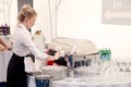 Russia Kemerovo 2019-07-27 Blonde waiter girl in uniform, white shirt, black apron at catering party prepares for banquet, make