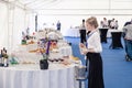 Russia Kemerovo 2019-07-27 Blonde waiter girl in uniform, white shirt, black apron at catering party prepares for banquet, make