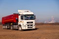 Russia Kemerovo 2019-04-09 red and white model Kamaz on field on background of city landscape and factory pipes. Concept truck on