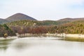 People boating around the swamp cypress trees and walk along the shore of a lake among the mountains in the warm autumn evening