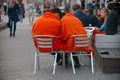 A pair of lovers covered with orange blankets,sit on bench in Gorky Park looking into mobile phone screen.