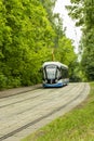 12-06-2019, Russia, Moscow. Blue Moscow tram moves on rails against the background of summer green foliage. Modern design of trams