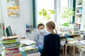 Russia Moscow 25.09.20 Little girl talks to librarian in face mask, asks,loos for book with fairy tales in children`s library.