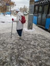 26.01.2022, Russia, Moscow. A lonely elderly woman with canes walking in her hands goes to a public transport stop.