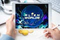 Russia Moscow 05.05.2021. Man holding tablet with logo of gaming platform Alien Worlds. Crypto coins,tokens mining online game.