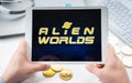 Russia Moscow 05.05.2021. Man holding tablet with logo of gaming platform Alien Worlds. Crypto coins,tokens mining online game.