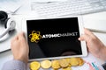 Russia Moscow 06.05.2021.Man holding tablet with logo of NFT marketplace Atomic market. Non fungible tokens for cryptocurrency WAX Royalty Free Stock Photo
