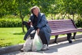 Russia Moscow 2019-06-17 Old sad woman sitting on bench with plastic bags in summer park outdoors. Aged homeless woman