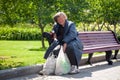 Russia Moscow 2019-06-17 Old sad woman sitting on bench with plastic bags in summer park outdoors. Aged homeless woman