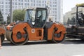 Russia, Moscow, 2019-08-10. An orange road roller stands near the road. Preparation for repair of the roadway
