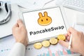 Russia Moscow 06.05.2021 Pancakeswap logo.Cryptocurrency decentralized exchange DEX, tablet.Trading blockchain platform to swap,