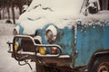 An old rusty ambulance van stands in a snow-covered clearing on a cloudy winter day.