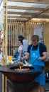 Russia, Moscow, 26-28th July 2019, BBQ festival in Moscow, Sokolniki park. Male chef in blue apron cooking meat on open fire durin