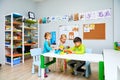 Russia, Moscow, 01.01.2019, two girls and a boy in kindergarten are sitting at a table and playing toys Royalty Free Stock Photo