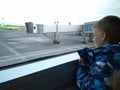 A child one small boy looks out the window at a tourist plane at the airport aviation flight on a