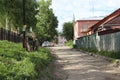 dirt road with parked cars in the village between houses in the summer