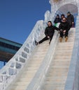 funny people ride from a high ice slide in the park in winter entertainment from a height