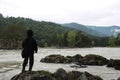 Russia,  a man boy stands on the bank of a river in the mountains with his back to a tourist hunter Royalty Free Stock Photo