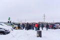 A lot of people on the Parking lot stand listening to a person speak into a microphone in winter Royalty Free Stock Photo