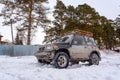 Offroad SUV `Suzuki Escudo` 4x4 with off-road training stands on a snowy road in the forest