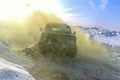 Russian off- road SUV `Lada Niva 4x4` quickly with a spray of snowstorm rides through the snow in winter in yellow Colored smoke