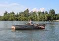 An old male fisherman swims in a boat on the river in the water