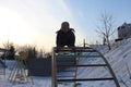 Russia, a small child climbed on a swing attraction in the snow in winter, it`s cold