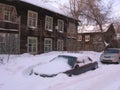 Snow-covered cars abandoned in the Parking lot in winter near wooden houses