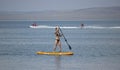 Stunning silhouette of a beautiful girl floating on on the surfboard