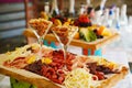 A wooden tray with cheese and meat appetizers on the banquet table.