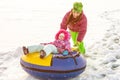 Russia, Ryazan 05 Jan 2019: happy woman with his family sliding down hill on snow tubes over winter natural background