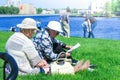 Two elderly women relax sitting on the lawn in the spring