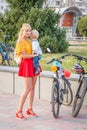 a beautiful, elegant participant, with a small child in her arms, a carnival costumed women`s bike ride on a summer evening