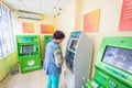 Mature beautiful woman pays utilities through the Sberbank ATM. Text in Russian: Sberbank, ATM