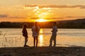 small children stand on the beach of the river and admire the beautiful sunset on a summer evening Royalty Free Stock Photo