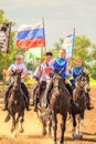 Russian young Cossacks gallop with banners on horses in summer sunny day.