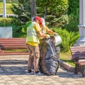 Utility workers collect garbage from an urn in a bag in a park