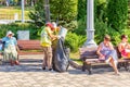 Utility workers collect garbage from an urn in a bag in a park