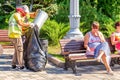 Utility workers collect garbage from an urn in a bag in a park