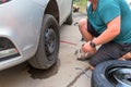 A young man changes a flat tire on a car on a summer day