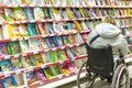 a woman in a wheelchair chooses a book for a child in the children`s department of the store. Royalty Free Stock Photo