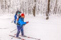 A skier runs along a ski track with a child in a backpack