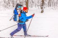 A skier runs along a ski track with a child in a backpack