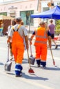 Community workers are walking along the street with a tool in their hands at work