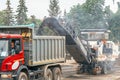 Cutting old asphalt with a special machine and loading it into a dump truck on a summer day. Royalty Free Stock Photo