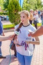 journalists interview an young beautiful volunteer girl on the Volga embankment in a warm summer sunny day.