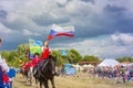 Solemn entry of a group of horse racing with flags in the meadow of the festival